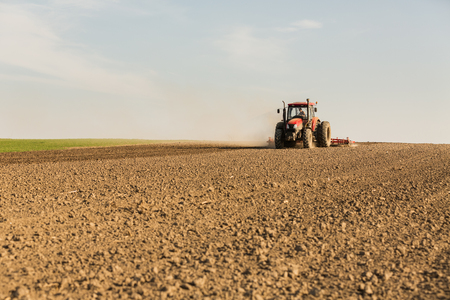 Farmer in tractor preparing land with seedbed cultivatorの写真素材