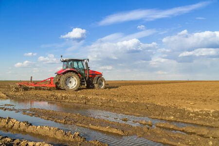 Farmer in tractor preparing land with seedbed cultivatorの写真素材