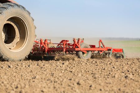 Farmer in tractor preparing land with seedbed cultivatorの写真素材