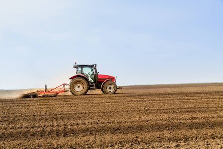 Farmer in tractor preparing land with seedbed cultivatorの写真素材
