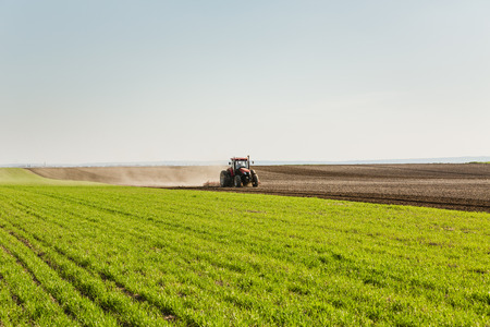 Farmer in tractor preparing land with seedbed cultivatorの写真素材