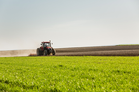 Farmer in tractor preparing land with seedbed cultivatorの写真素材