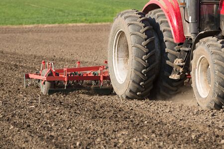 Farmer in tractor preparing land with seedbed cultivatorの写真素材