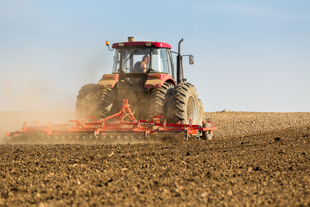 Farmer in tractor preparing land with seedbed cultivatorの写真素材