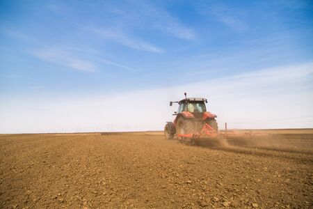 Farmer in tractor preparing land with seedbed cultivatorの写真素材