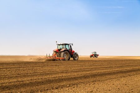 Farmer in tractor preparing land with seedbed cultivatorの写真素材