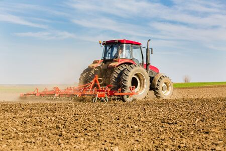 Farmer in tractor preparing land with seedbed cultivatorの写真素材