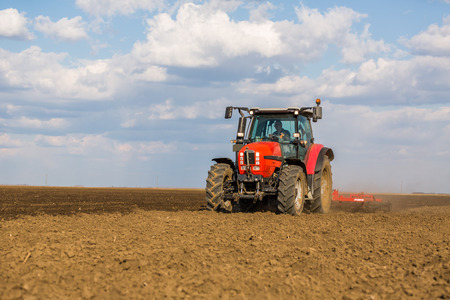 Farmer in tractor preparing land with seedbed cultivatorの写真素材