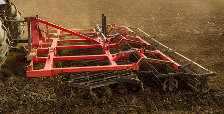 Farmer in tractor preparing land with seedbed cultivator as part of pre seeding activities in early spring season of agricultural works at farmlands.の写真素材