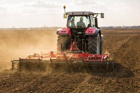 Farmer in tractor preparing land with seedbed cultivatorの写真素材