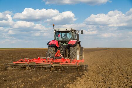 Farmer in tractor preparing land with seedbed cultivatorの写真素材