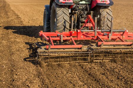 Farmer in tractor preparing land with seedbed cultivatorの写真素材