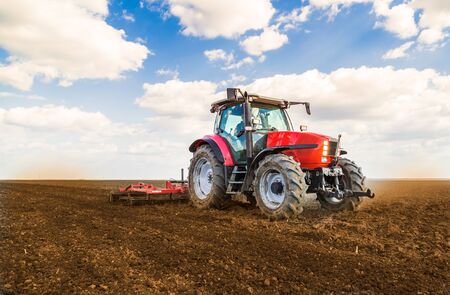 Farmer in tractor preparing land with seedbed cultivatorの写真素材