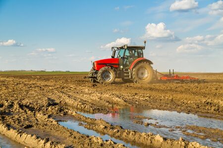 Farmer in tractor preparing land with seedbed cultivatorの写真素材