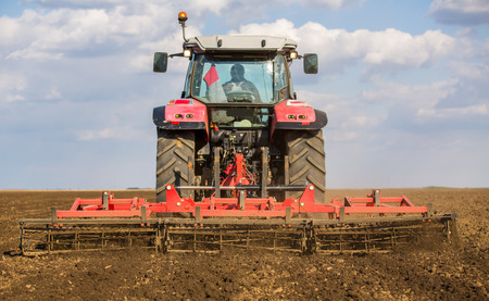 Farmer in tractor preparing land with seedbed cultivatorの写真素材