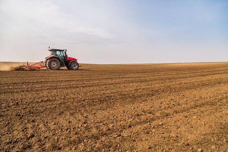 Farmer in tractor preparing land with seedbed cultivatorの写真素材