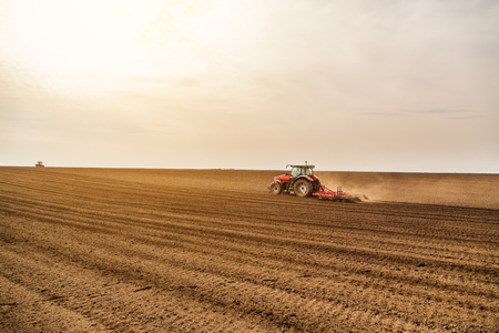Farmer in tractor preparing land with seedbed cultivatorの写真素材