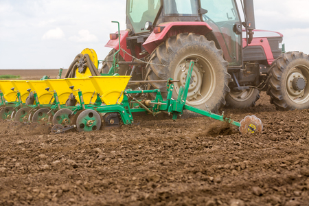 Farmer seeding, sowing crops at field. Sowing is the process of planting seeds in the ground as part of the early spring time agricultural activities.の写真素材