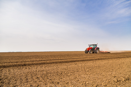 Farmer in tractor preparing land with seedbed cultivatorの写真素材