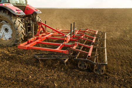 Farmer in tractor preparing land with seedbed cultivator as part of pre seeding activities in early spring season of agricultural works at farmlands.の写真素材