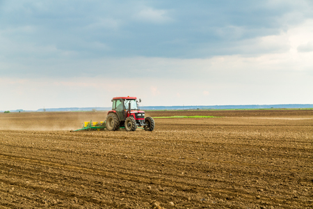 Farmer seeding, sowing crops at field. Sowing is the process of planting seeds in the ground as part of the early spring time agricultural activities.の写真素材