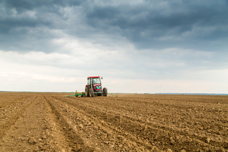 Farmer seeding, sowing crops at field. Sowing is the process of planting seeds in the ground as part of the early spring time agricultural activities.の写真素材
