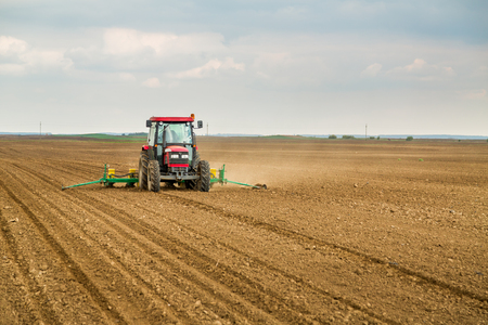 Farmer seeding, sowing crops at field. Sowing is the process of planting seeds in the ground as part of the early spring time agricultural activities.の写真素材