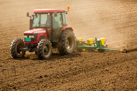 Farmer seeding, sowing crops at field. Sowing is the process of planting seeds in the ground as part of the early spring time agricultural activities.の写真素材