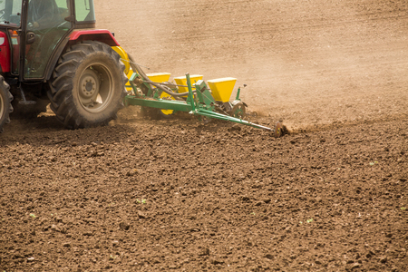 Farmer seeding, sowing crops at field. Sowing is the process of planting seeds in the ground as part of the early spring time agricultural activities.の写真素材