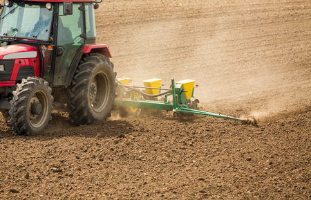 Farmer seeding, sowing crops at field. Sowing is the process of planting seeds in the ground as part of the early spring time agricultural activities.の写真素材