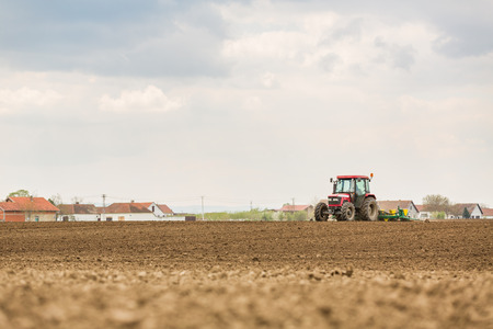 Farmer seeding, sowing crops at field. Sowing is the process of planting seeds in the ground as part of the early spring time agricultural activities.の写真素材
