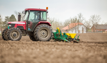 Farmer seeding, sowing crops at field. Sowing is the process of planting seeds in the ground as part of the early spring time agricultural activities.の写真素材