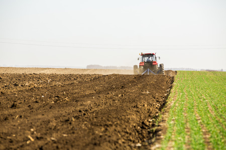 Farmer in tractor preparing land with seedbed cultivator as part of pre seeding activities in early spring season of agricultural works at farmlands.の写真素材