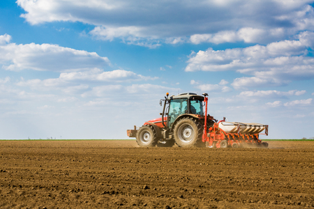 Farmer seeding, sowing crops at field. Sowing is the process of planting seeds in the ground as part of the early spring time agricultural activities.の写真素材
