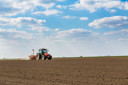 Farmer seeding, sowing crops at field. Sowing is the process of planting seeds in the ground as part of the early spring time agricultural activities.の写真素材