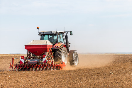 Farmer seeding, sowing crops at field. Sowing is the process of planting seeds in the ground as part of the early spring time agricultural activities.の写真素材