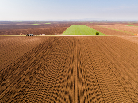 Aerial shot of a farmer seeding, sowing crops at field. Sowing is the process of planting seeds in the ground as part of the early spring time agricultural activities.の写真素材