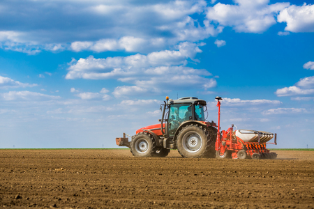 Farmer seeding, sowing crops at field. Sowing is the process of planting seeds in the ground as part of the early spring time agricultural activities.の写真素材