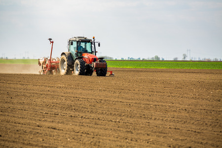 Farmer seeding, sowing crops at field. Sowing is the process of planting seeds in the ground as part of the early spring time agricultural activities.の写真素材