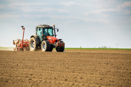 Farmer seeding, sowing crops at field. Sowing is the process of planting seeds in the ground as part of the early spring time agricultural activities.の写真素材
