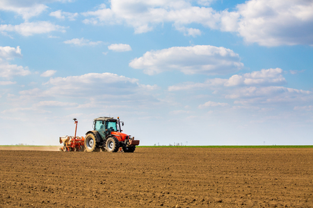 Farmer seeding, sowing crops at field. Sowing is the process of planting seeds in the ground as part of the early spring time agricultural activities.の写真素材
