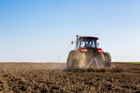 Tractor cultivating field at springの写真素材