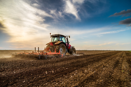 Tractor cultivating field at springの写真素材