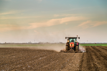 Tractor cultivating field at springの写真素材