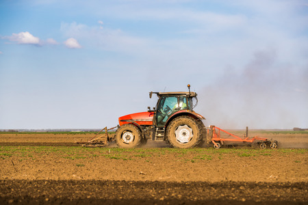 Tractor cultivating field at springの写真素材