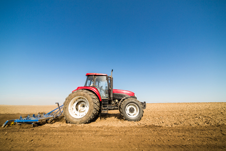 Tractor cultivating field at springの写真素材
