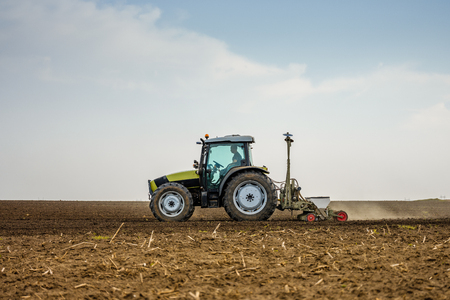 Farmer seeding, sowing crops at field. Sowing is the process of planting seeds in the ground as part of the early spring time agricultural activities.の写真素材