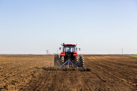 Tractor cultivating field at spring