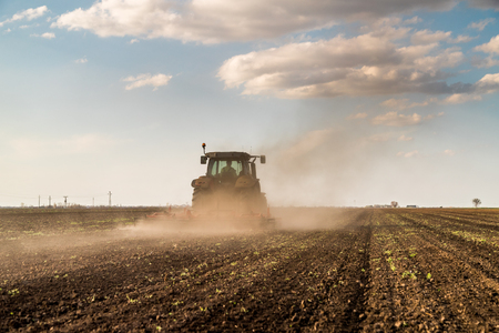 Farmer in tractor preparing land with seedbed cultivator as part of pre seeding activities in early spring season of agricultural works at farmlands.の写真素材