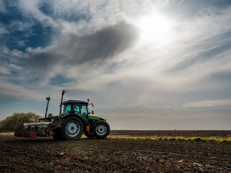 Farmer seeding, sowing crops at field. Sowing is the process of planting seeds in the ground as part...